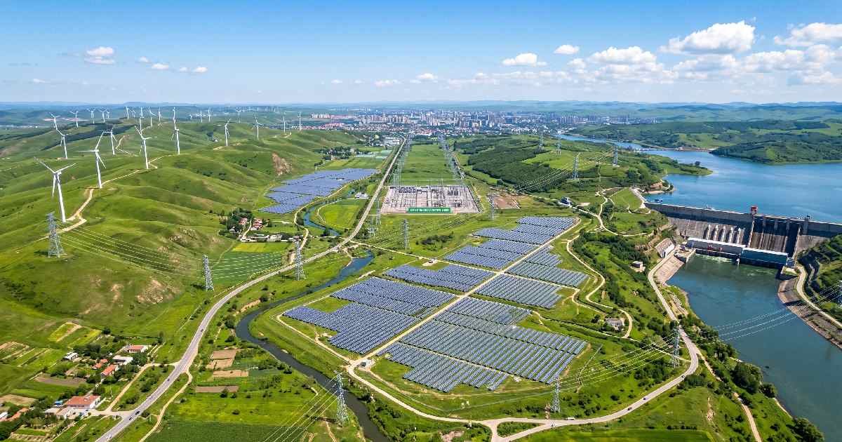 Aerial view of wind turbines, solar farms, and hydropower connected by power lines enabling the renewable grid.