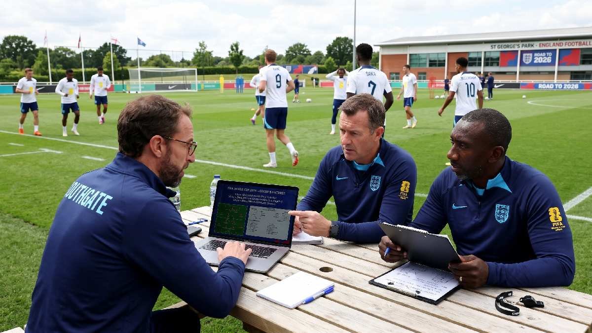 England coaching staff studying FIFA World Cup 2026 group stage match plan on laptop with players warming up in background.