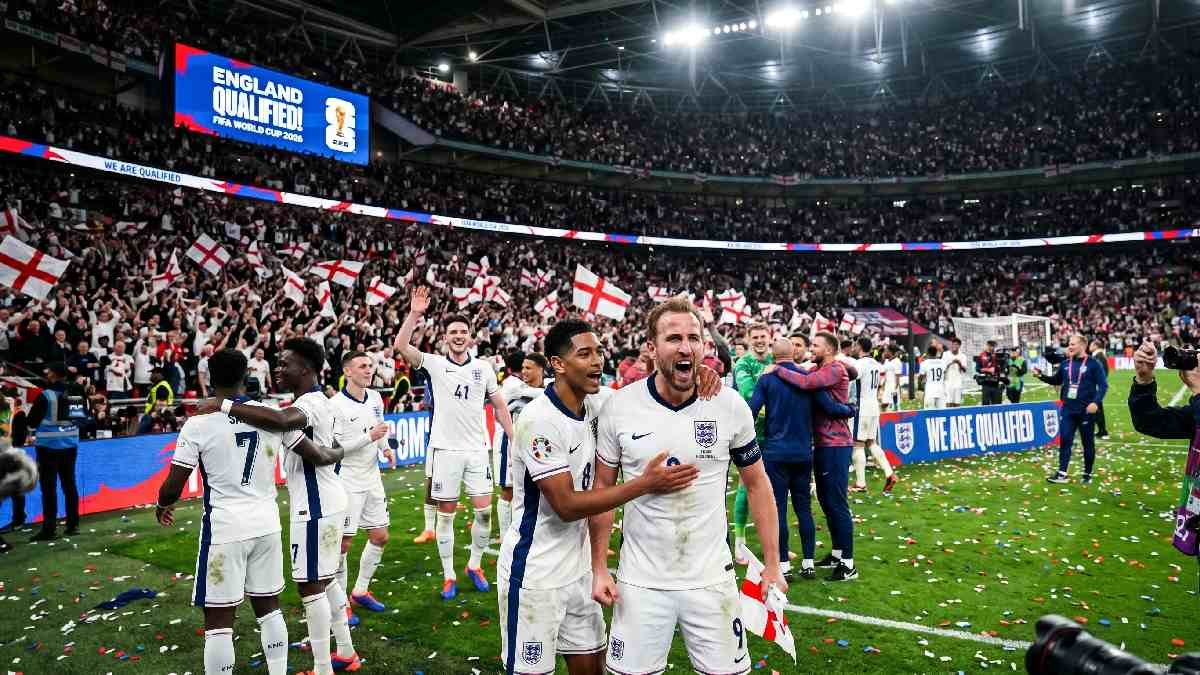 England national football team celebrating FIFA World Cup 2026 qualification on pitch with fans waving St George's Cross flags.