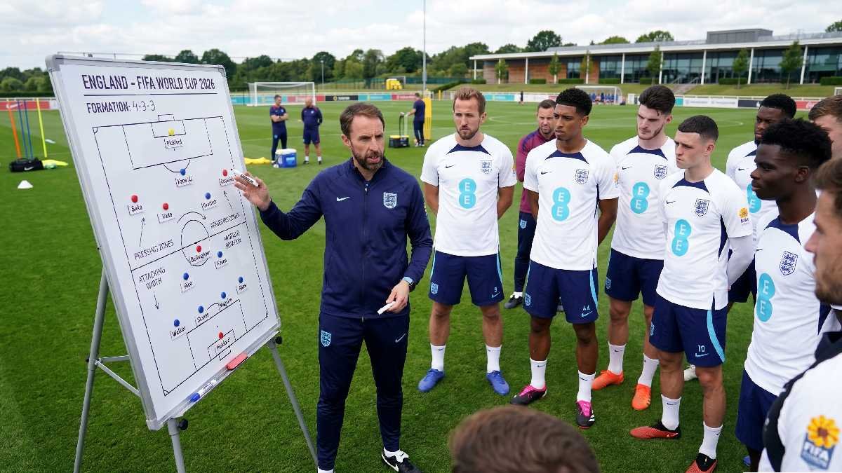England manager explaining tactical formation on whiteboard to players during FIFA World Cup 2026 training session.