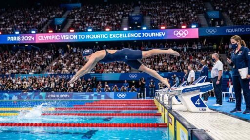 Determined Olympic swimmer diving into the competition pool, representing the journey from Olympic vision to aquatic excellence.