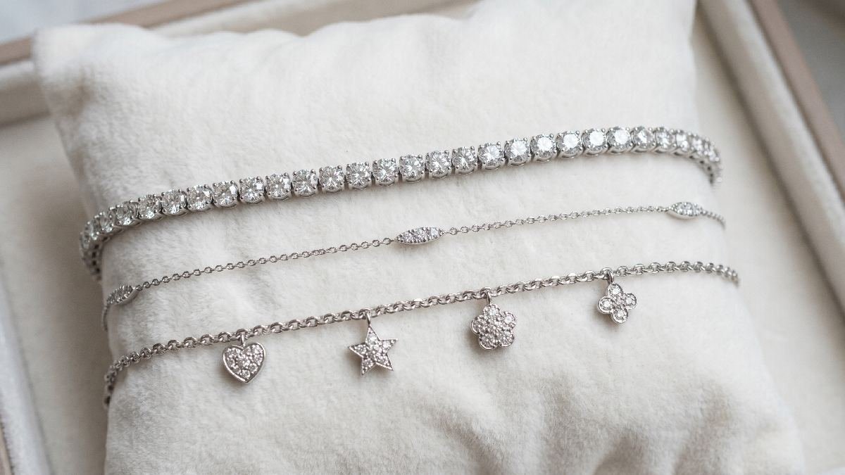 Three diamond bracelets on white velvet showing tennis, thin, and charm styles for different occasions and events.