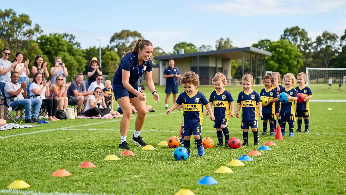 Young coach leading fun toddler football class with colorful cones and mini balls on a bright sunny grass field.